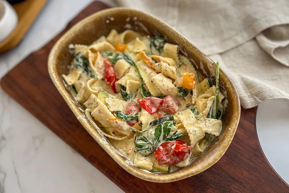 Cremige Bandnudeln mit Kirschtomaten, Zucchini und Spinat in einer rustikalen Auflaufform
